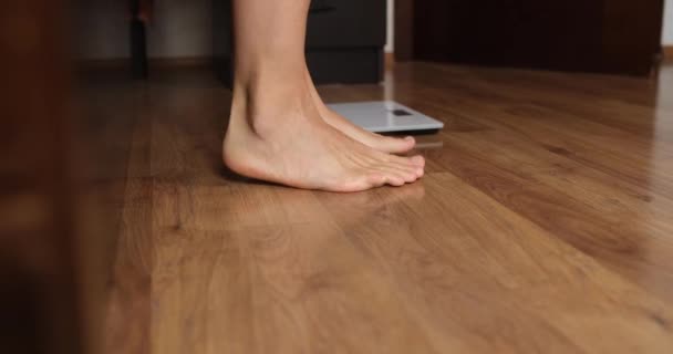 Una persona viene pesata dopo il sonno, i piedi sul pavimento primo piano. Gioia di perdita di peso, controllo del peso, misurazione - Filmati, video