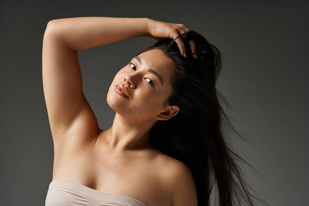 Esmer saçlı, sivilceli genç Asyalı kadın banyodaki aynaya bakıyor. - Fotoğraf, Görsel