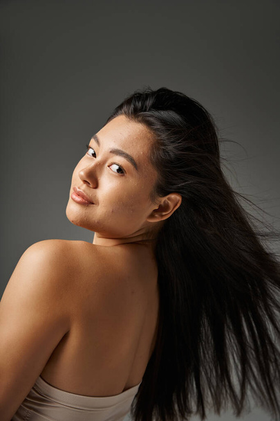 jeune femme asiatique avec des cheveux bruns et l'acné peau sujette à regarder miroir dans la salle de bain, bannière - Photo, image