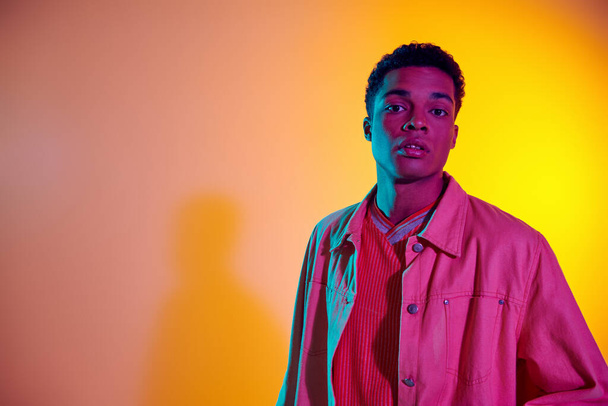 young african american man posing in trendy and casual clothing with vibrant gradient background - Photo, Image