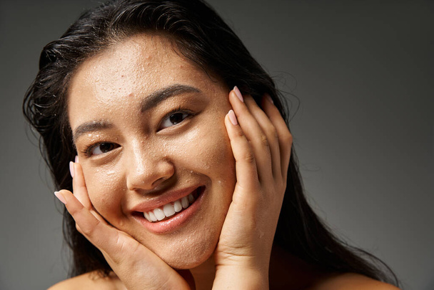 mujer asiática joven con pelo morena y piel propensa al acné mirando el espejo en el baño, pancarta - Foto, Imagen