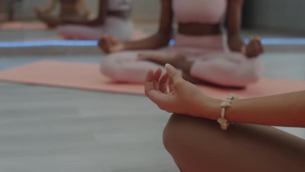グループワーク中にロタスポーズで瞑想する女性ヨギの手に焦点を当てたクロップショット - 映像、動画