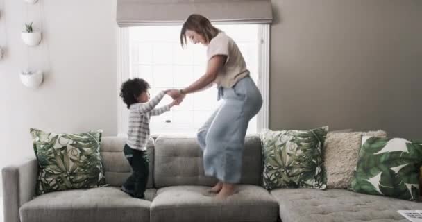 Familie, Sprung und eine Mutter mit ihrem Sohn auf einem Sofa im Wohnzimmer ihres Hauses zusammen zum Spaß. Freiheit, Energie oder Liebe mit einer Frau und einem Kind, die auf einer Couch in der Lounge spielen, um sich zu verbinden. - Filmmaterial, Video