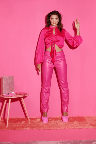 verleidelijke jonge vrouw in gewas top en roze broek gebaren onnatuurlijk en gedragen als een pop - Foto, afbeelding