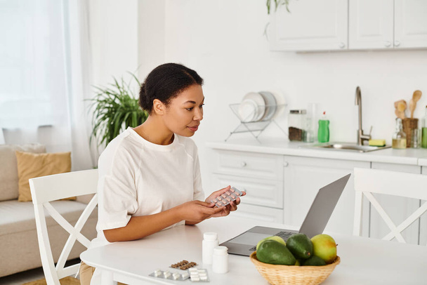 gelukkig Afrikaans-Amerikaanse voedingsdeskundige met pillen op zoek naar laptop tijdens een online consult - Foto, afbeelding