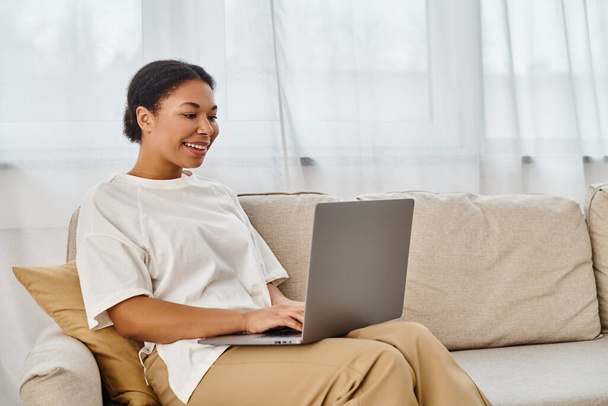 feliz nutricionista afro-americano usando laptop enquanto trabalhava em casa na sala de estar - Foto, Imagem