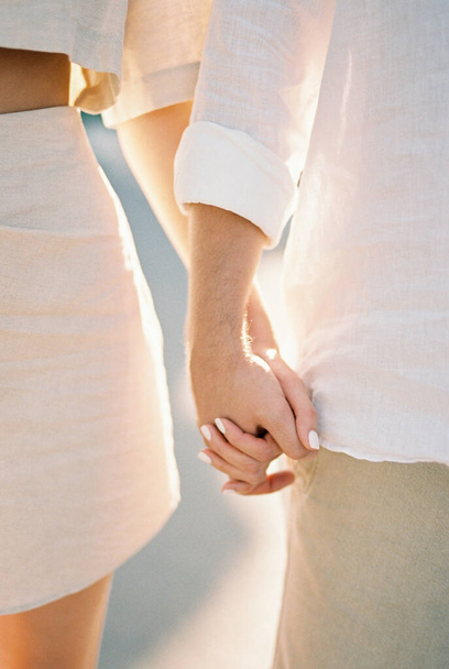 Чоловік і жінка стоять, тримаючись за руки. Обрізаний. Безликий. Високоякісна фотографія - Фото, зображення