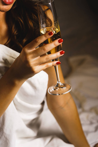 Seksowna kobieta pozująca ze szklanką szampana w pokoju hotelowym. Koncepcja urlopu - Zdjęcie, obraz
