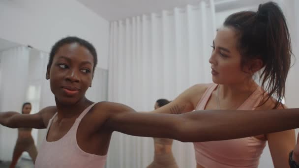 Toma de mano de una mujer afroamericana que practica yoga posando mientras hace ejercicio en el estudio con una entrenadora - Metraje, vídeo