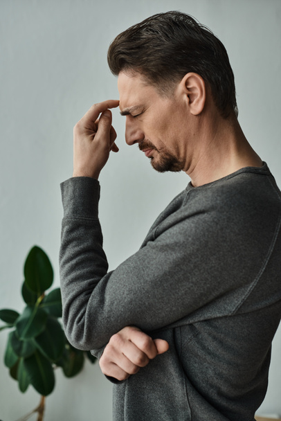 gestresste en bebaarde man met gesloten ogen fronsen terwijl hij thuis hoofdpijn heeft, migraine - Foto, afbeelding