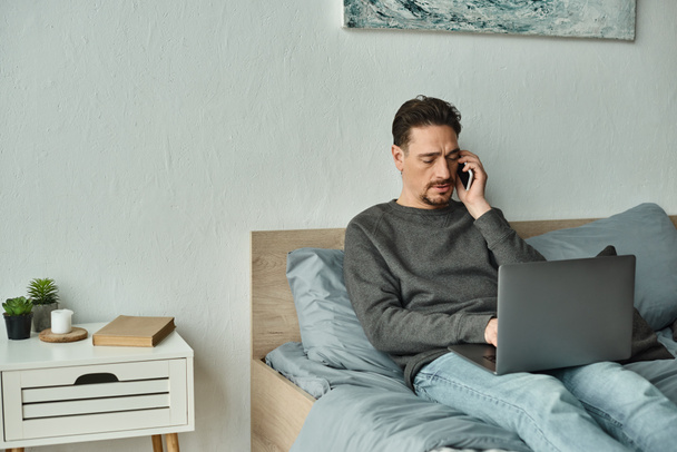 brodaty człowiek za pomocą laptopa i rozmowy na smartfonie podczas pracy zdalnie z domu, freelance - Zdjęcie, obraz