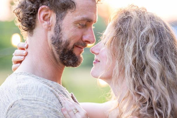 A close-up captures a tender moment between a man and woman as they gaze into each others eyes. The man, possibly of Middle-Eastern descent, and the woman, with her curly blonde hair, share a close - Photo, Image