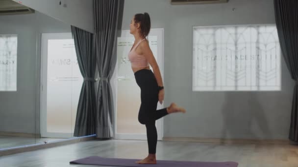 Dlouhý záběr sportovkyně vyvažování při stání na jedné noze s nataženou rukou při cvičení ve fitness studiu, kopírovací prostor - Záběry, video