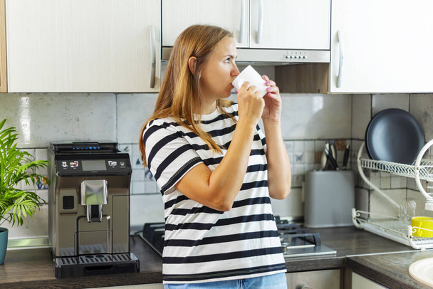 Attraktive Frau genießt morgens frisch zubereiteten Kaffee in der Küche. - Foto, Bild