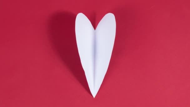4k Büyük beyaz kalp kanatlarını çırpıyor. Aşkın sembolü. Tebrik kartı. Sevgililer Günü tatili, düğün ve aşkı ifade etmek için diğer fırsatlar kavramı. Kırmızı arka plan. Hareket animasyonunu durdur. Düz yatıyordu. - Video, Çekim
