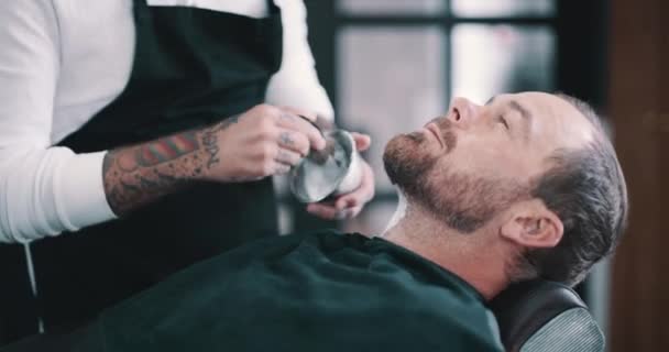 Barbershop ludzi, krem do brody i klienta cięcia do pielęgnacji twarzy, konserwacji lub zabiegu fryzjerskiego. Sprzęt fryzjerski, klient i fryzjer ręce z pędzlem do golenia creme aplikacji. - Materiał filmowy, wideo