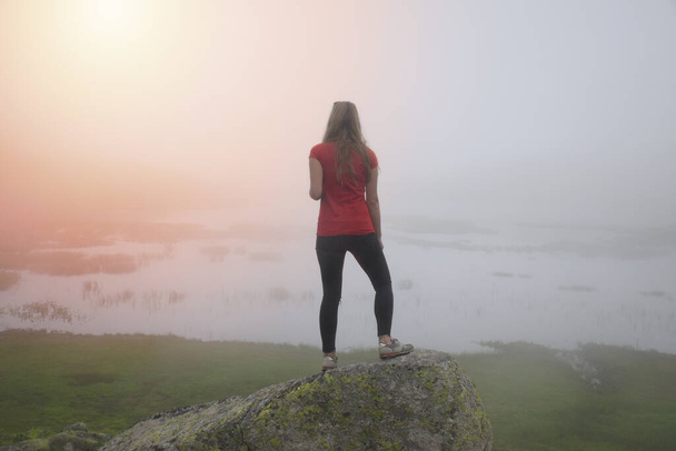 Fiatal lány nézi a ködös völgyet és tavat. - Fotó, kép