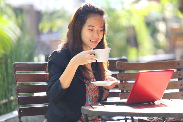 young businesswoman using laptop and drinking coffee outdoors. - Foto, afbeelding
