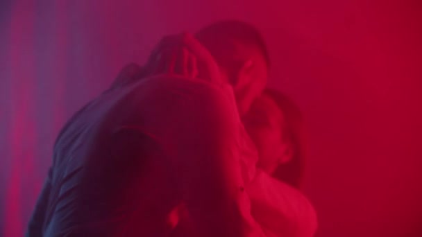 Paar küsst Vorspiel auf Neonlicht Hintergrund. Junge kaukasische Männer und Frauen flirten einfühlsam. Familie in einem intimen Moment drinnen. Leidenschaftliche Liebhaber Küsse in Nachtclub. Hochwertiges 4k Filmmaterial - Filmmaterial, Video