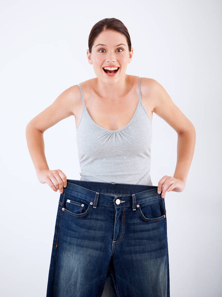 Kobieta, schudnąć i portret zaskoczenia dżinsy, zmiana rozmiaru lub białe tło w studio. Wow, zszokowany i osoba z szaloną transformacją w fitness, zdrowie lub porównanie w dżinsach. - Zdjęcie, obraz