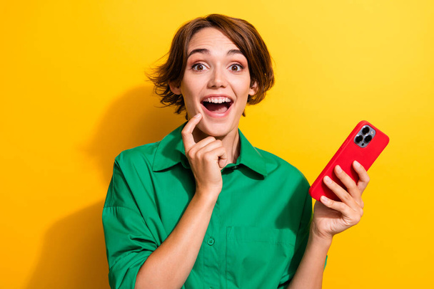 Photo of excited impressed lady wear green shirt getting sms apple iphone samsung modern device isolated yellow color background. - Zdjęcie, obraz