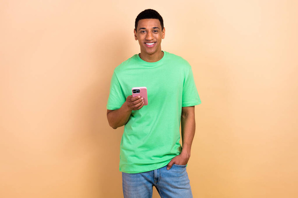 Photo portrait of nice young male hold device comment post wear trendy green outfit isolated on beige color background. - Foto, immagini
