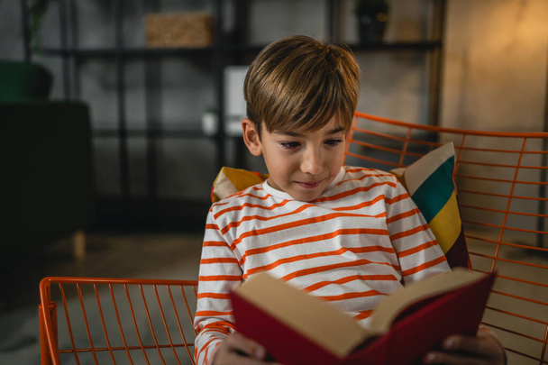 Een blanke jongen thuis las een boek in de avond front view kopieerruimte echte mensen onderwijs concept - Foto, afbeelding