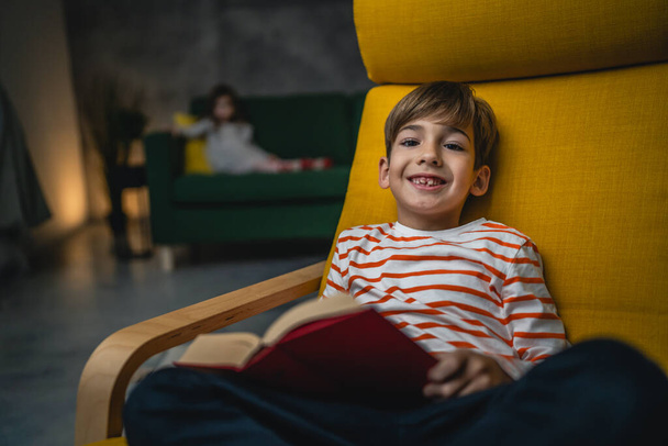 Um menino caucasiano em casa ler um livro à noite vista frontal cópia espaço pessoas reais educação conceito - Foto, Imagem