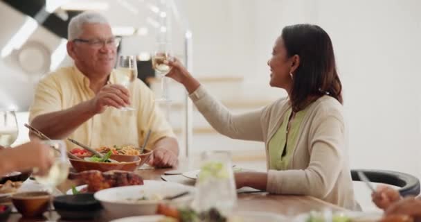 Family, dinner and food with cheers or wine at dining table for bonding, event or conversation in living room of home. Love, elderly and people with alcohol for lunch, supper or brunch with smile. - Séquence, vidéo