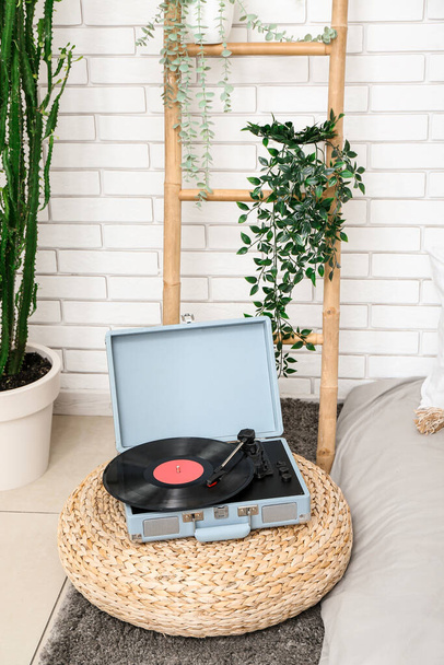 Record player with vinyl disk on pouf in bedroom - Photo, Image