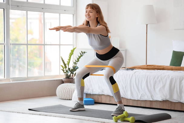 Junge sportliche Frau trainiert zu Hause mit Gummiband - Foto, Bild