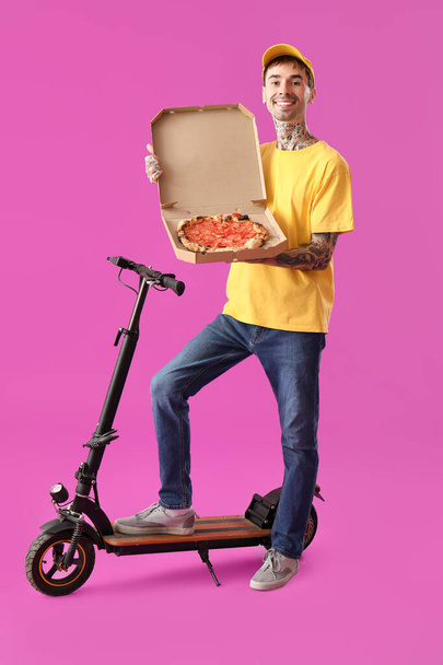 Männlicher Mitarbeiter eines Essenslieferdienstes mit leckerer Pizza und Tretroller auf lila Hintergrund - Foto, Bild