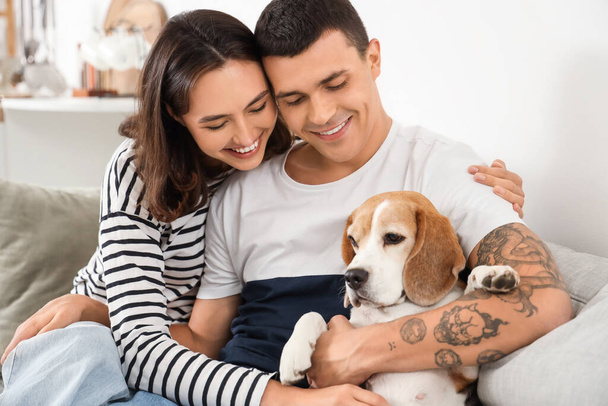 Νεαρό ζευγάρι με χαριτωμένο σκυλί Beagle στο σπίτι - Φωτογραφία, εικόνα
