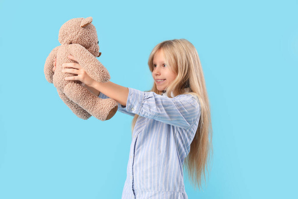 Schattig klein meisje met pluche teddybeer op blauwe achtergrond - Foto, afbeelding