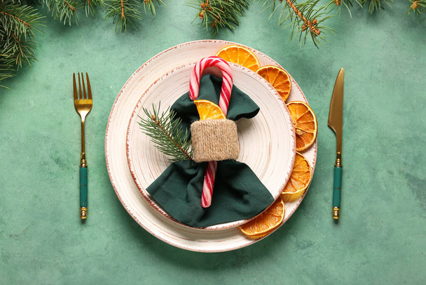 Schöne weihnachtliche Tischdekoration mit getrockneten Orangenscheiben und Zuckerrohr auf grünem Hintergrund - Foto, Bild