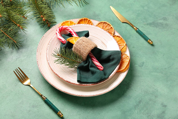 Όμορφη ρύθμιση χριστουγεννιάτικο τραπέζι με αποξηραμένα φέτες πορτοκαλιού και ζαχαροκάλαμο καραμέλα σε πράσινο φόντο - Φωτογραφία, εικόνα