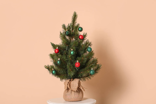 Piccolo albero di Natale sullo sgabello vicino alla parete beige - Foto, immagini