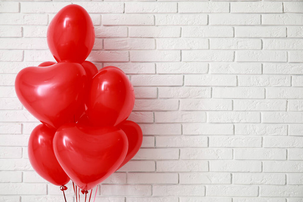 Vzduchové balónky ve tvaru srdce na bílém cihlovém pozadí. Valentýnská oslava - Fotografie, Obrázek