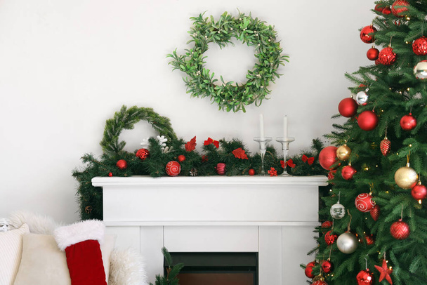 Chimenea con hermosa decoración de Navidad cerca de la pared de luz - Foto, Imagen