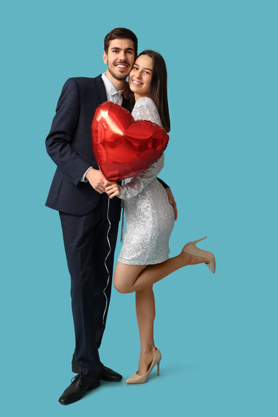 Piękna młoda para z balonem w kształcie serca na niebieskim tle. Walentynki święto - Zdjęcie, obraz