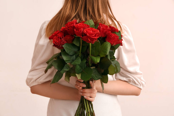 Fiatal nő csokor gyönyörű vörös rózsa fehér háttérrel. Valentin-napi ünneplés - Fotó, kép