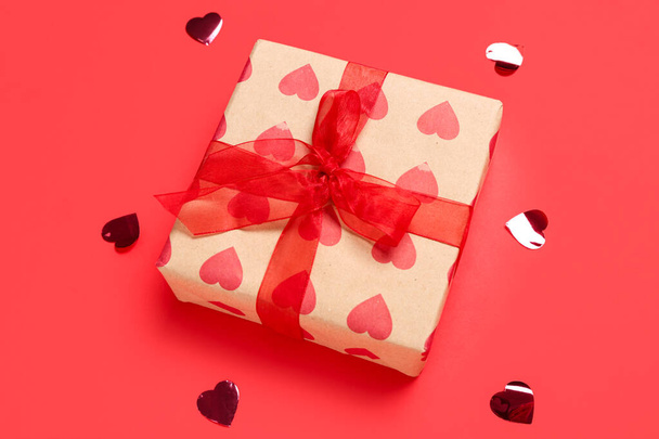 Gift box and confetti on red background. Valentine's Day celebration - Photo, Image