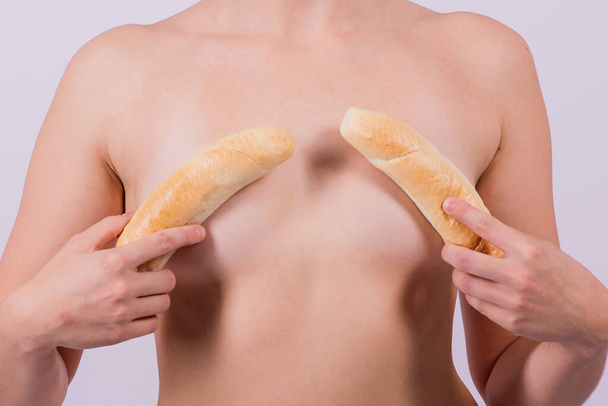 Female sensual body holding one big a white bread bun with sesame seeds, horizontal picture - Fotografie, Obrázek