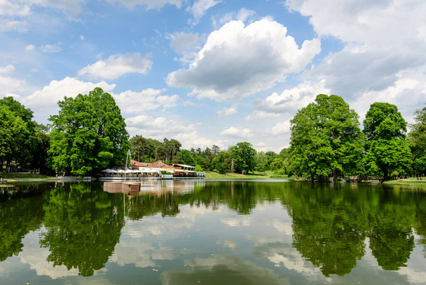 2022年5月28日 ルーマニア・カイオヴァ: ニコライ・ロマネスク公園の美しい風景,湖,ウォーターリリース,青空と白雲の美しい晴れた春の日に大きなグリーンウィーク - 写真・画像