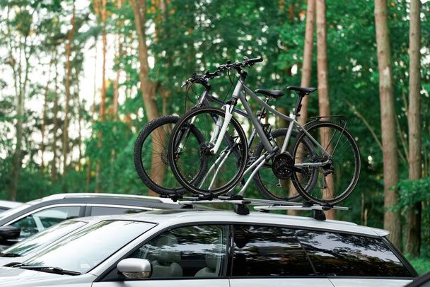 Samochód osobowy z dwoma rowerami zamontowanymi na dachu. Pojęcie sportu i wakacji na świeżym powietrzu - Zdjęcie, obraz