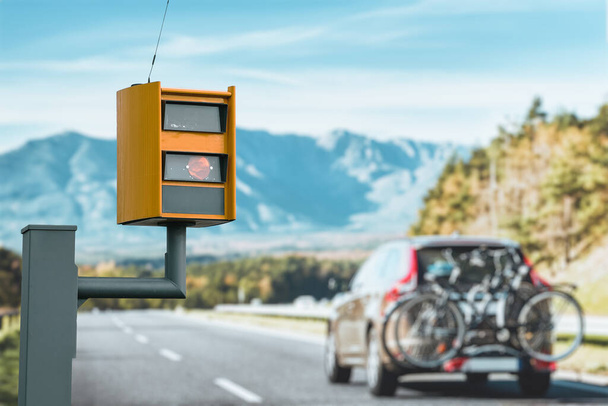 Uma câmera de velocidade equipada com radar monitora o tráfego em uma estrada, exibindo uma luz amarela quando pega um carro que excede o limite de velocidade e usa a tecnologia para identificar o veículo e fazer cumprir a lei. - Foto, Imagem