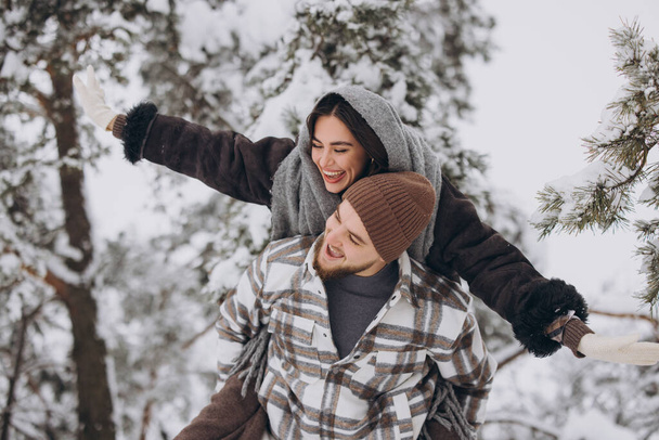 Una giovane coppia felice e amorevole si sta divertendo in una foresta innevata in inverno. - Foto, immagini