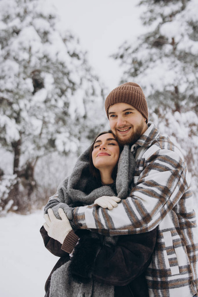 Un jeune couple heureux et aimant s'amuse dans une forêt enneigée en hiver. - Photo, image