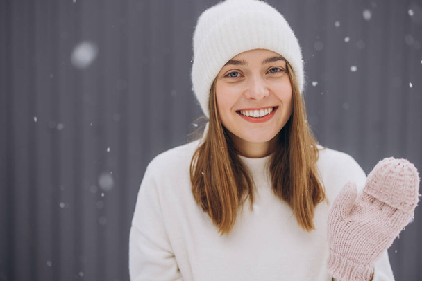 Happy young woman in knitted mittens waving greeting in snowy weather in winter - Photo, Image