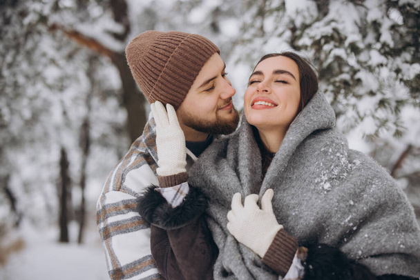 Πορτρέτο ενός νεαρού ευτυχισμένου και αγαπημένου ζευγαριού που διασκεδάζει σε ένα χιονισμένο δάσος - Φωτογραφία, εικόνα